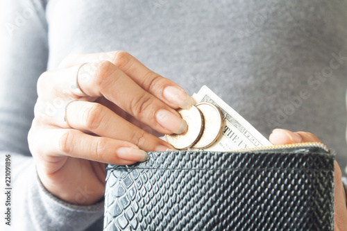 Woman holding wallet with coins and paper currency