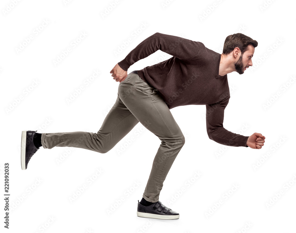 A fit bearded man in casual sweater stands in a low running position with only one foot on the ground. A fit bearded man in casual sweater stands in a low running position with only one foot on the ground.