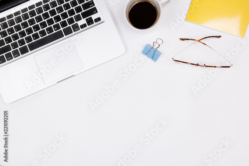 Home office desk workspace with coffee cup, glasses and laptop on white background. Flat lay for entrepreneur. Small business concept. Top view.