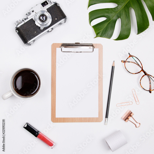 Clipboard mockup with tropical palm leaf, vintage camera, glasses and coffee cup on white background. Flat lay, top view woman blog mockup. summer travel concept.