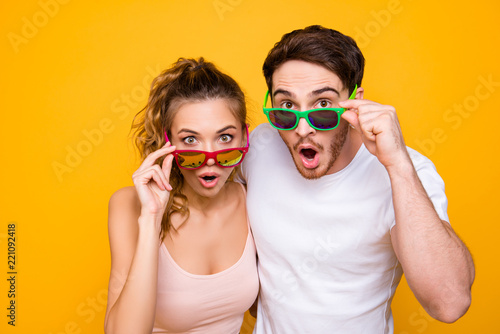 Portrait of shocked surprised couple looking out eyeglasses at c