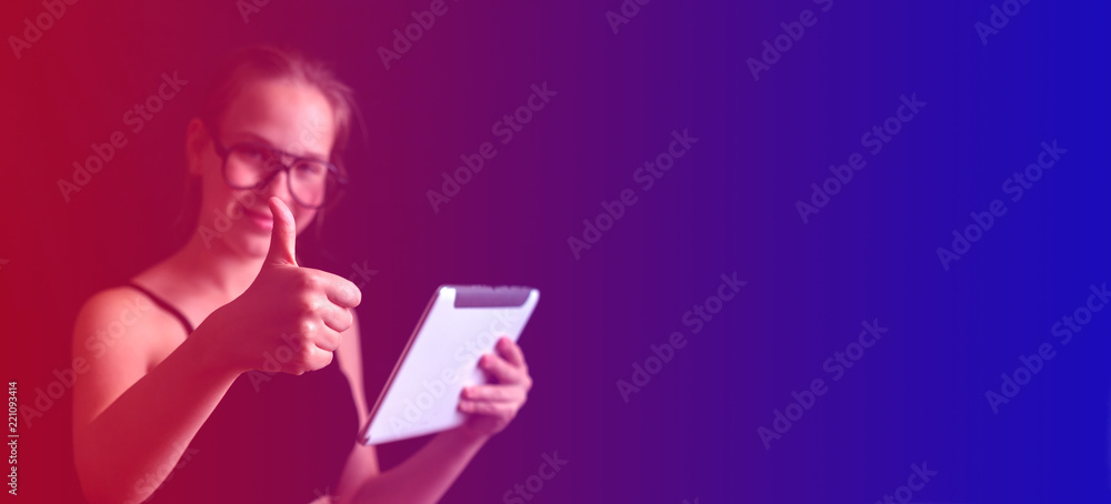 girl in glasses with a tablet makes a choice of buying on a toned background, the concept of online sales of discount news long banner