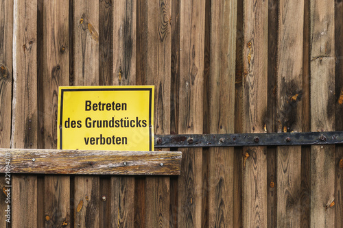 Schild Betreten des Grundstücks verboten an einem alten Holztor
