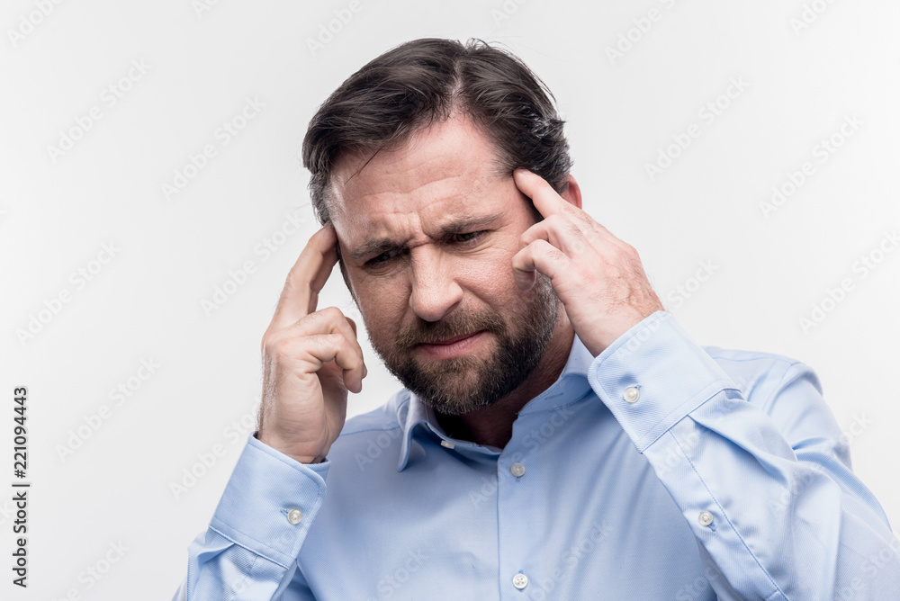 Strong headache. Image without face retouching with dark-haired businessman suffering from strong headache at work Strong headache. Image without face retouching with dark-haired businessman suffering from strong headache at work