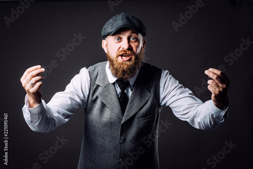 A bearded man in suit talking and gesticulating like italian on black background