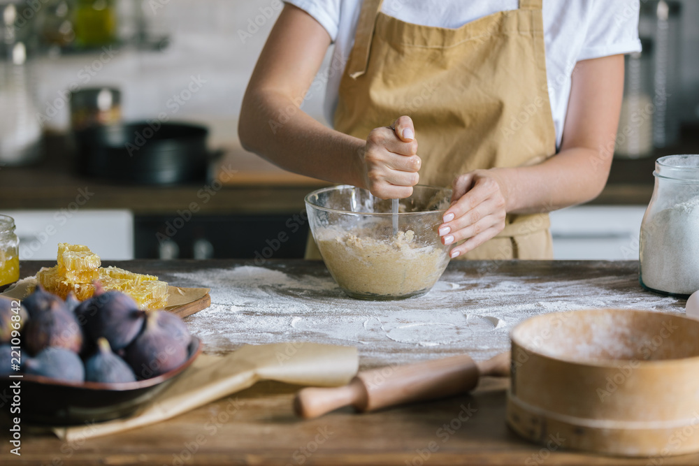 cropped shot of woman mixing dough for pie with spoon on rustic wooden table