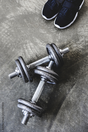 top view of adjustable dumbbells with sneakers on concrete surface