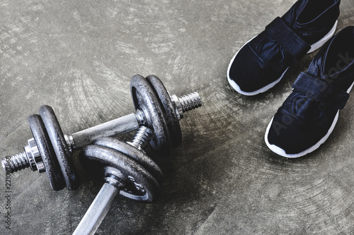 close-up shot of adjustable dumbbells with sneakers on concrete surface