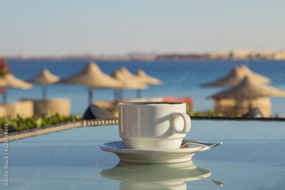 white cup of coffee on the table at sea. Summer holiday concept.