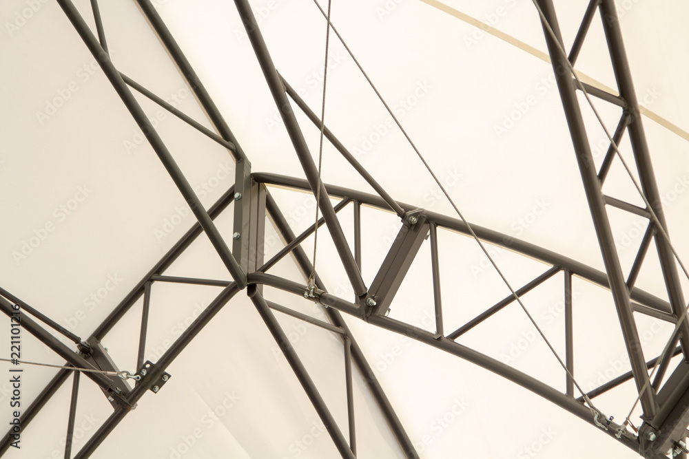 Metal frame of the outer structure against the background of a light canvas. The construction of the roof of the metal frame scene. Cables and frame.