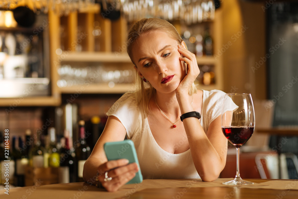 Where is the message. Nice sad woman looking at her smartphone while waiting for the message