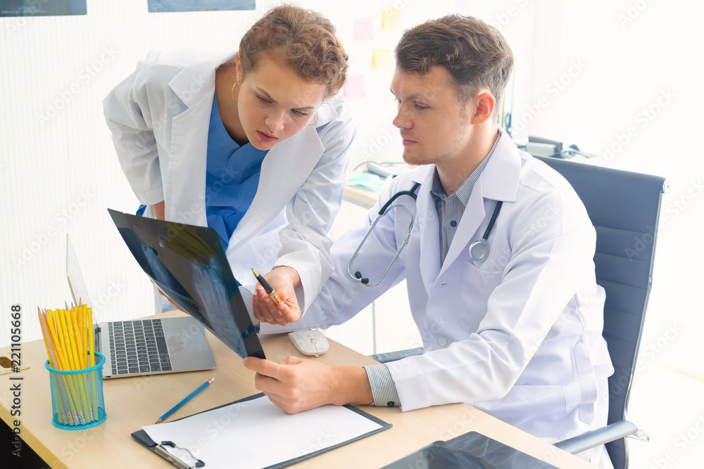 Doctor and nurse assistant are reading the x-ray film in the nursing room, feeling suspicious Doctor and nurse assistant are reading the x-ray film in the nursing room, feeling suspicious