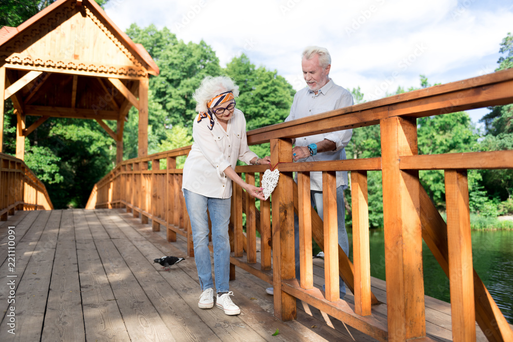 Eternal love. Couple of good-looking beaming pensioners showing the world eternal love hanging heart on bridge Eternal love. Couple of good-looking beaming pensioners showing the world eternal love hanging heart on bridge