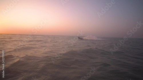 Dawn shooting, a man slides on the waves on kitesurf. Leaks photo