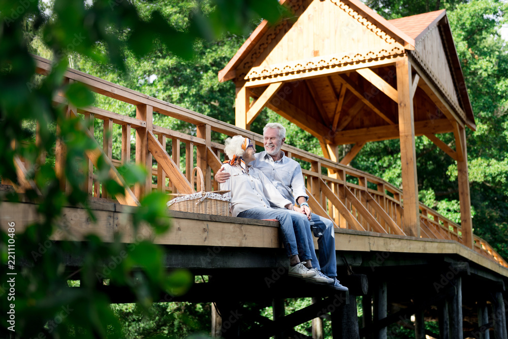 Looking at wife. Bearded elderly man feeling lovely while looking at his beautiful fashionable wife having picnic Looking at wife. Bearded elderly man feeling lovely while looking at his beautiful fashionable wife having picnic