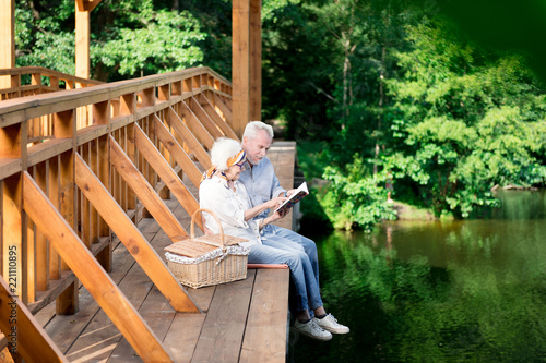 Traditional picnic. Retired wife and husband feeling relaxed while having traditional family picnic near the lake