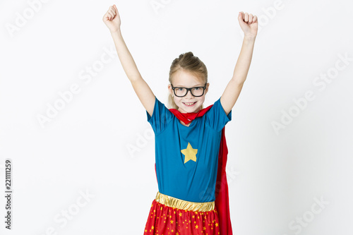 Платно blond supergirl with glasses and red robe und blue shirt is posing in the studio