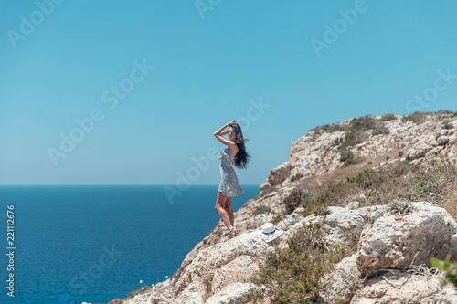 Girl on the edge of a cliff overlooking the sea in a dress © cmirnovalexander