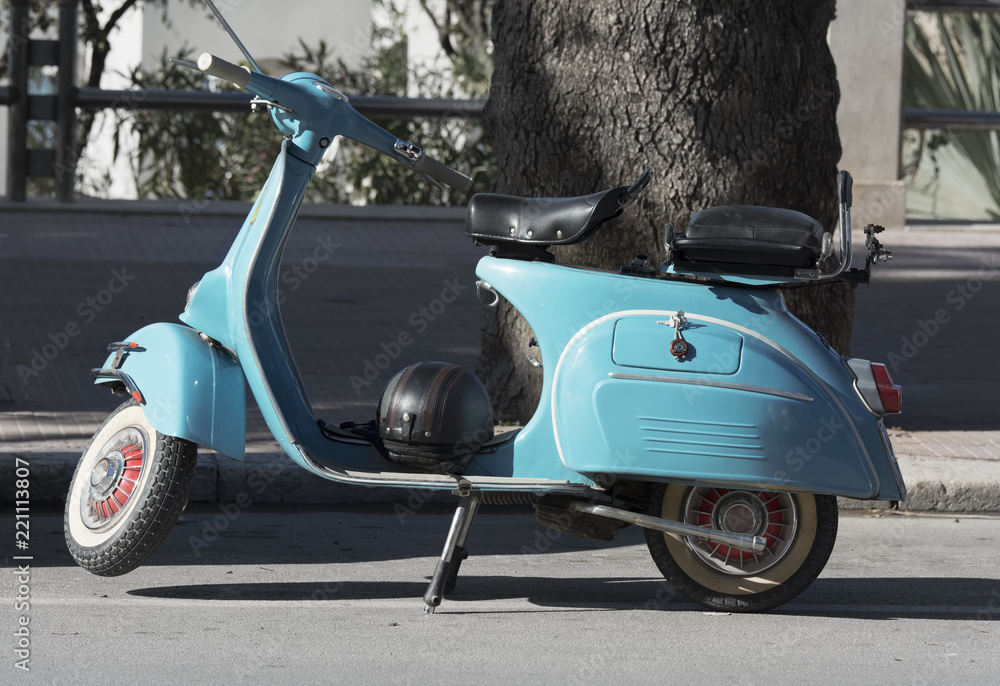 Old blue scooter parked on empty street.