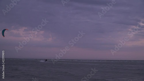 A man in the background of the cloudy sky is engaged in kitesurfing photo