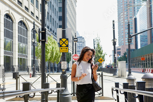 Businesswoman using cellphone by barriers photo