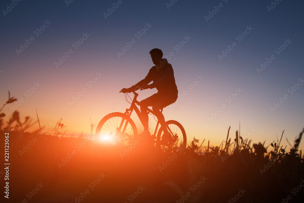 Silhouette of the cyclist riding a road bike at sunset Silhouette of the cyclist riding a road bike at sunset