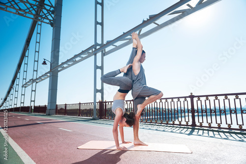 Couples practice. Focused appealing man and woman doing pose while staying on bridge