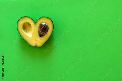 Heart-shaped avocado on  green background