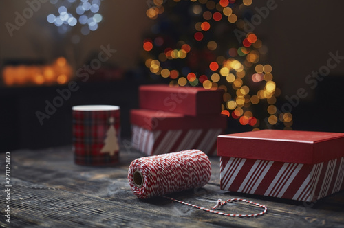 Roll of red-white packthread and gift boxes in front of lighted Christmas tree