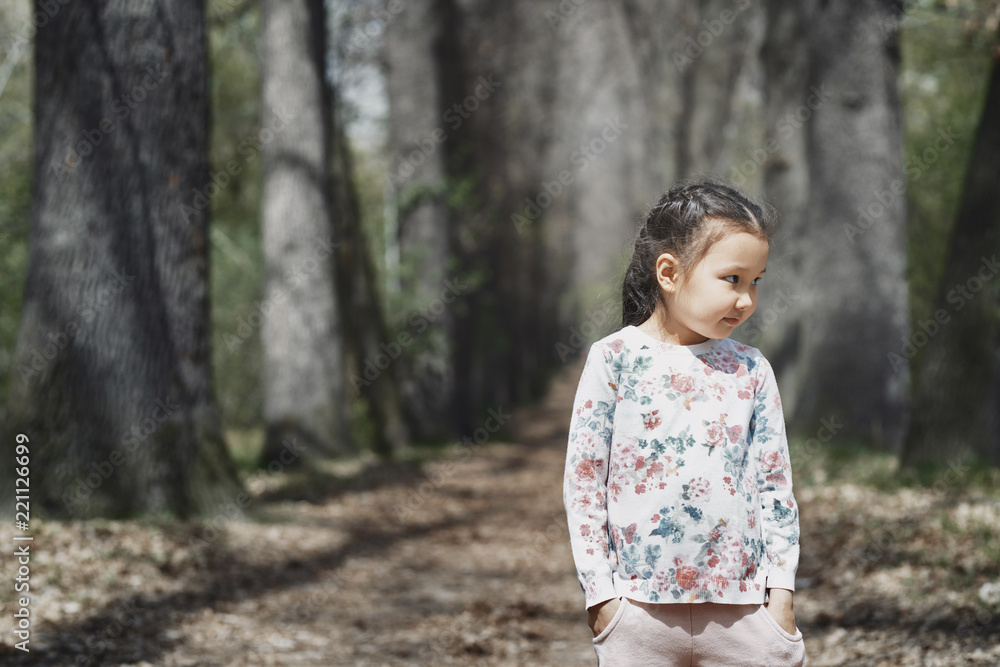 Little girl standing in park, with hands in pockets Little girl standing in park, with hands in pockets