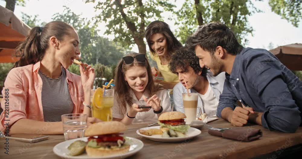 Five multiethnic friends sitting at table in cafe, talking on phone with someone, and laughing. People enjoying theit time together 4k Five multiethnic friends sitting at table in cafe, talking on phone with someone, and laughing. People enjoying theit time together 4k