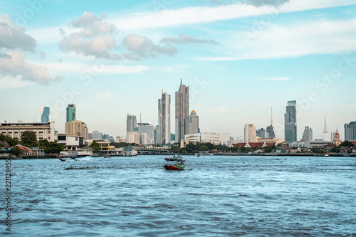 View of Bangkok skyline with the skyscrapers in background and Chao Phraya River in the foreground during bright sunny day, Bangkok, Thailand