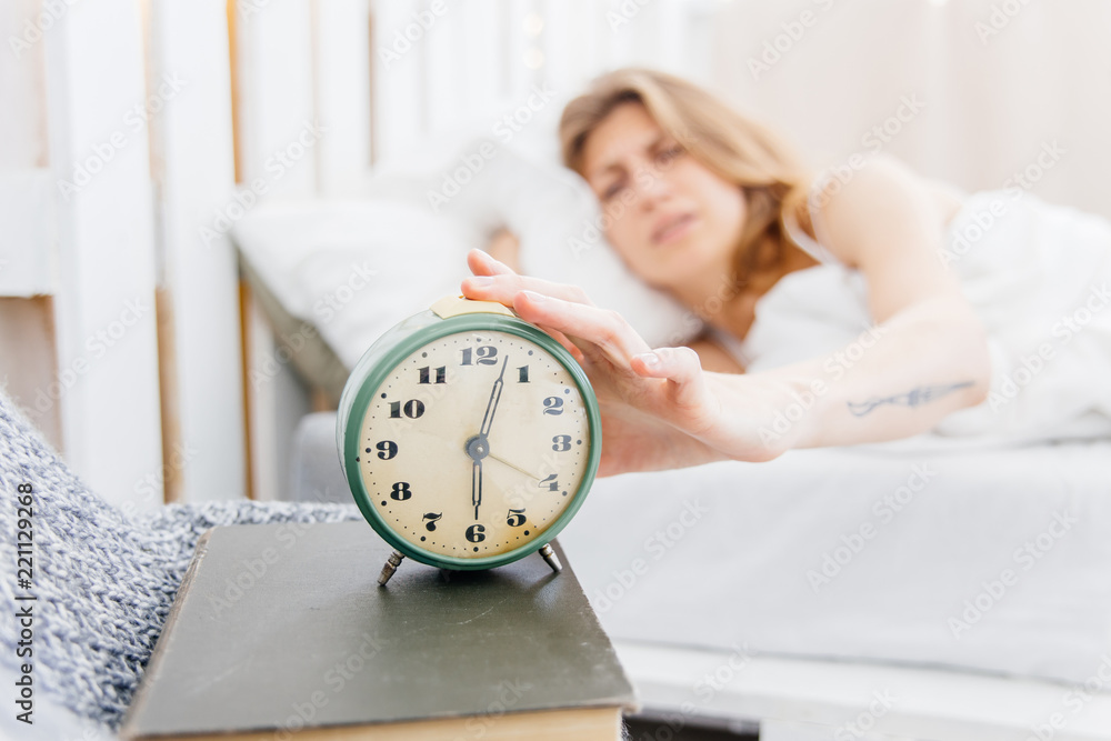 Young woman turns off the alarm clock in the morning Young woman turns off the alarm clock in the morning