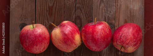four red ripe apples on a wooden background