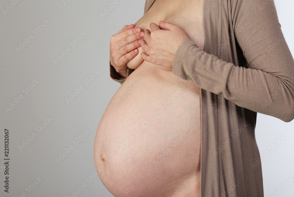 Pregnant woman with belly covers the chest hand Stock Photo