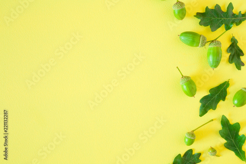 Beautiful, fresh green oak leaves and acorns on bright yellow table. Greeting card. Mockup for different ideas. Empty place for inspirational text, quote or sayings. Flat lay. Top view.