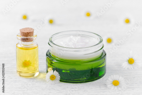 care products, natural cream and massage oil with fresh chamomile flowers