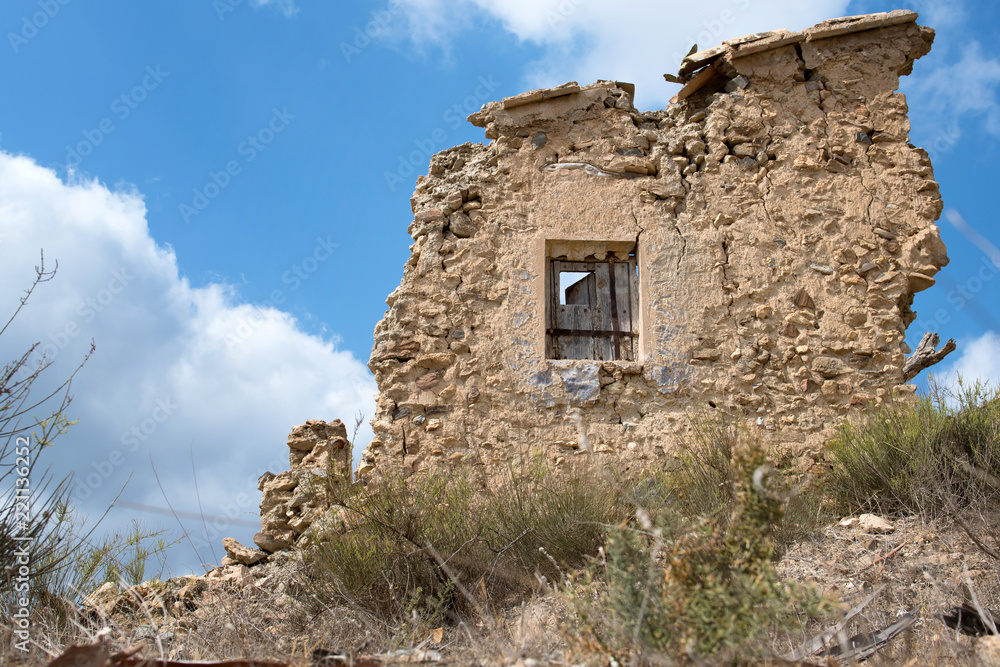 The ruin of a house in arid countryside.