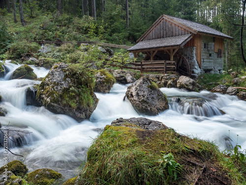 Idyllic long exposure view of an old abandoned mill with rocks lying in beautiful riverbed in a mystic forest on a cloudy moody day in springtime, Golling, Salzburger Land, Austria. August, 2018 photo