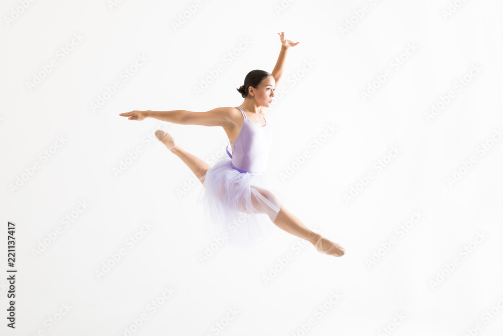 Fototapeta premium Young Ballerina Doing Splits In The Air Against White Background