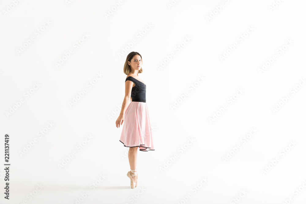 Female Ballet Dancer Maintaining Balance Over White Background Female Ballet Dancer Maintaining Balance Over White Background