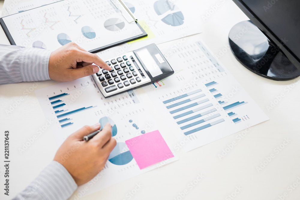 Business man working at office with laptop, tablet and graph data documents on his desk Business man working at office with laptop, tablet and graph data documents on his desk