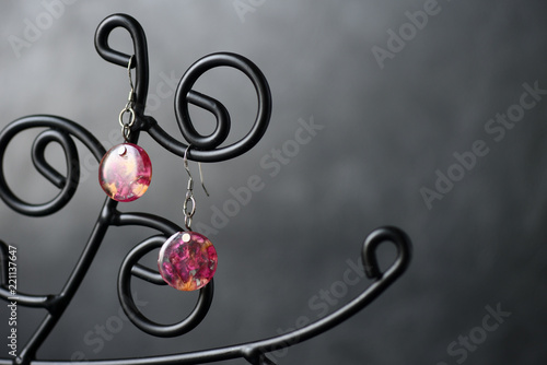 Resin earrings with dry rose petals on a dark background close up