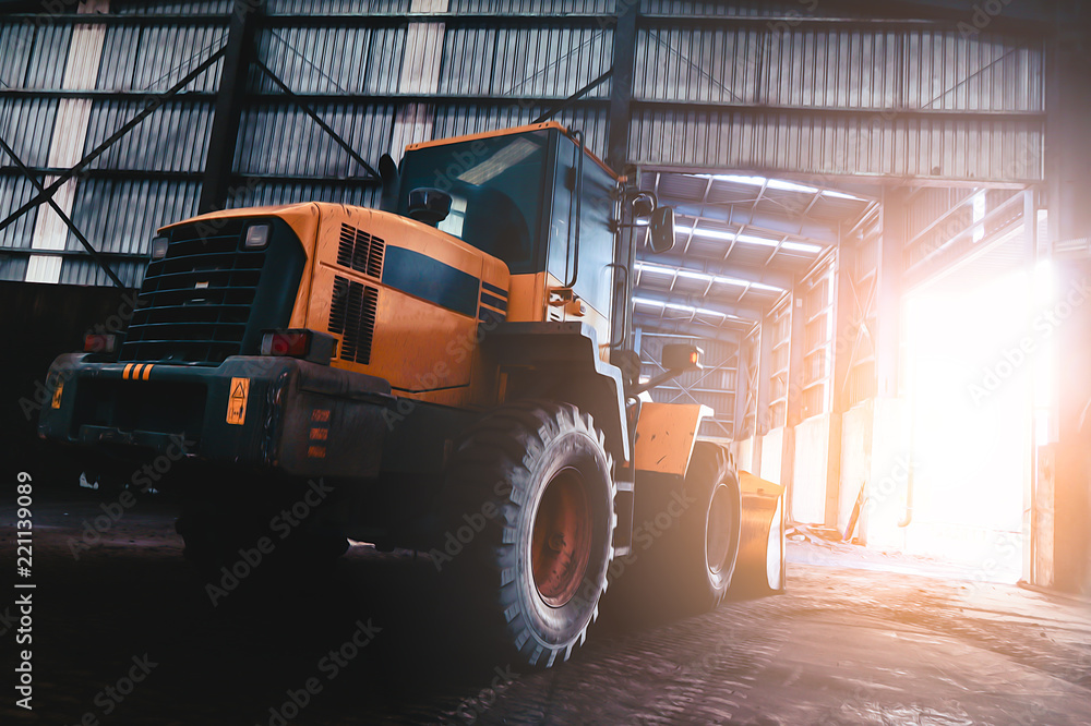 Obraz premium Heavy wheel loader excavator machine loading sand at quarry in a warehouse.