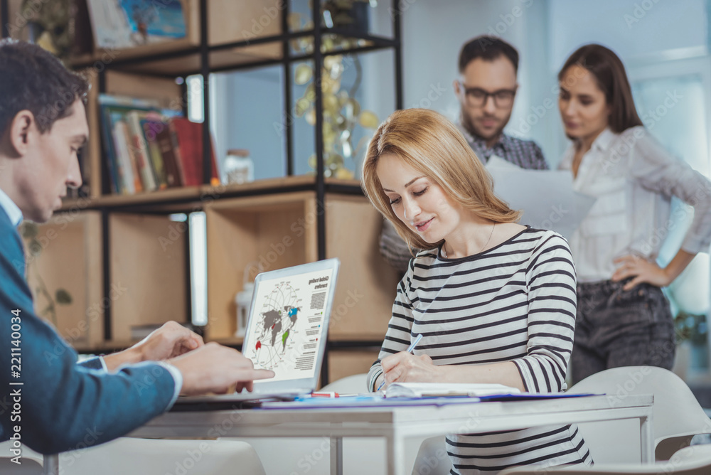 Hard workers. Low angle of attractive two colleagues working and sitting at table Hard workers. Low angle of attractive two colleagues working and sitting at table