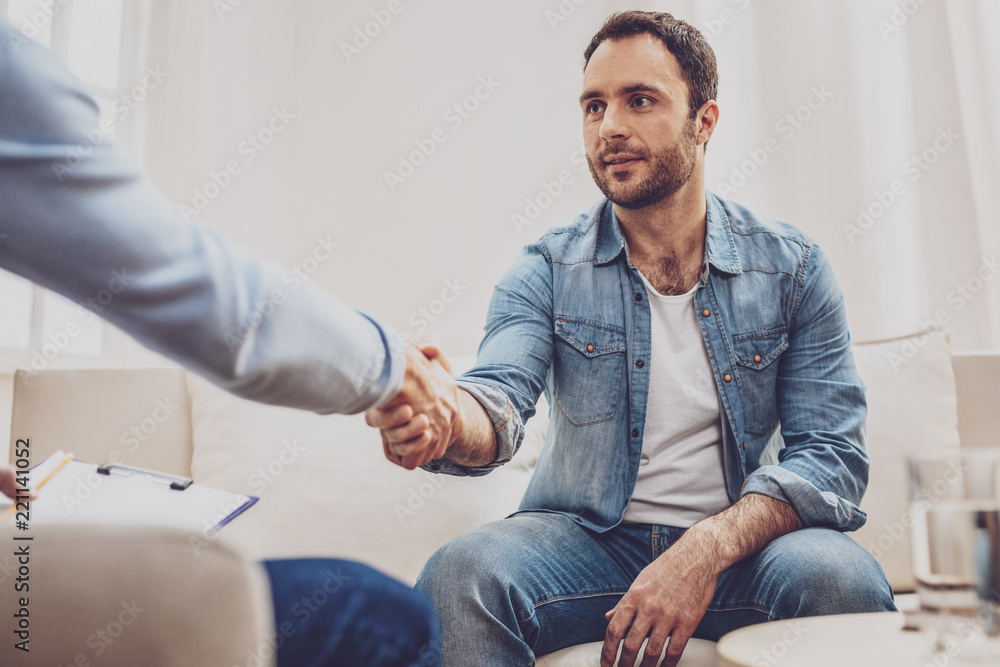 Obraz premium Good morning. Pleasant handsome man shaking hands with his psychologist while greeting him