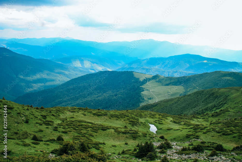 Naklejka premium The summer green Carpathian mountains in Ukraine. The sky is over the mountains. Atmospheric landscapes while traveling on a jeep. Offroad expedition