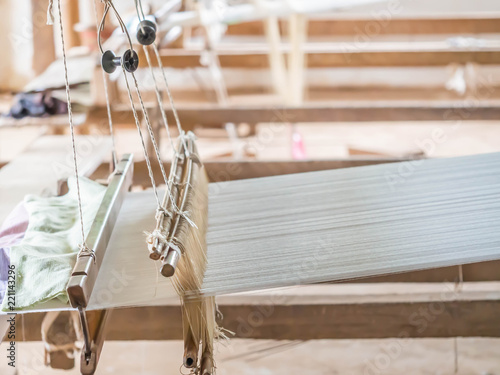Closeup of wooden loom with white cotton thread for weaving.