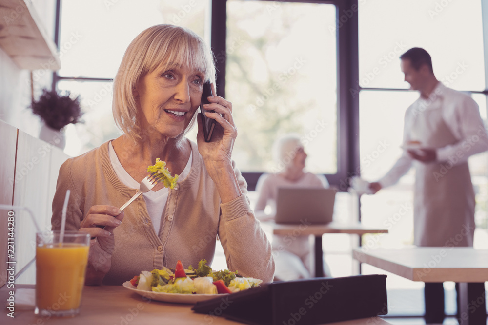 Important call. Occupied pleasant senior woman spending time in the cafe having conversation and eating. Important call. Occupied pleasant senior woman spending time in the cafe having conversation and eating.