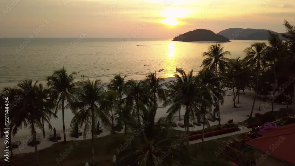 Unique orange sunset Tropical exotic beach white sand Palm trees recreation area hotels territory. Islands horizon. Nature landscape. People walk. Travel tourism. Langkawi Maldives. Aerial Side drift Unique orange sunset Tropical exotic beach white sand Palm trees recreation area hotels territory. Islands horizon. Nature landscape. People walk. Travel tourism. Langkawi Maldives. Aerial Side drift